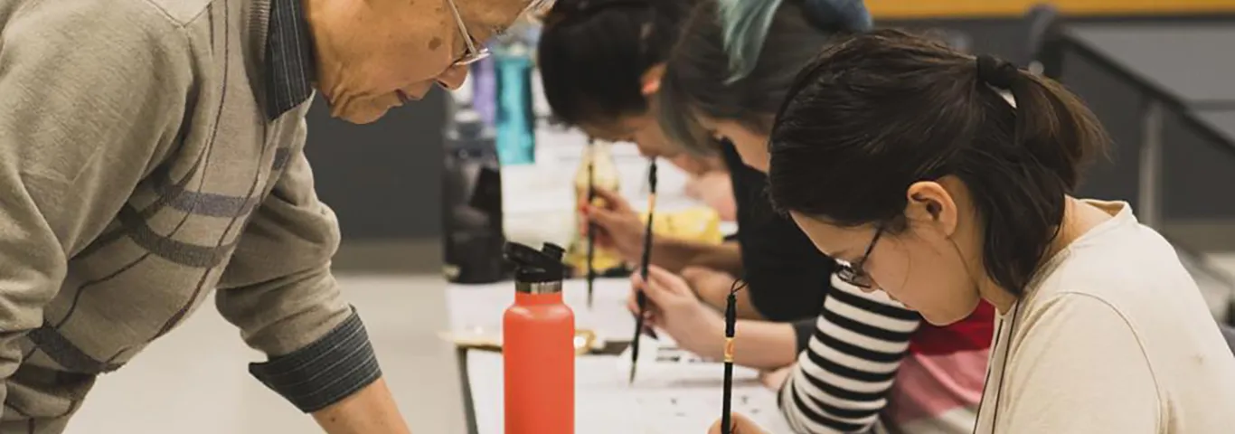 Professor Fred Wu watches students practicing calligraphy